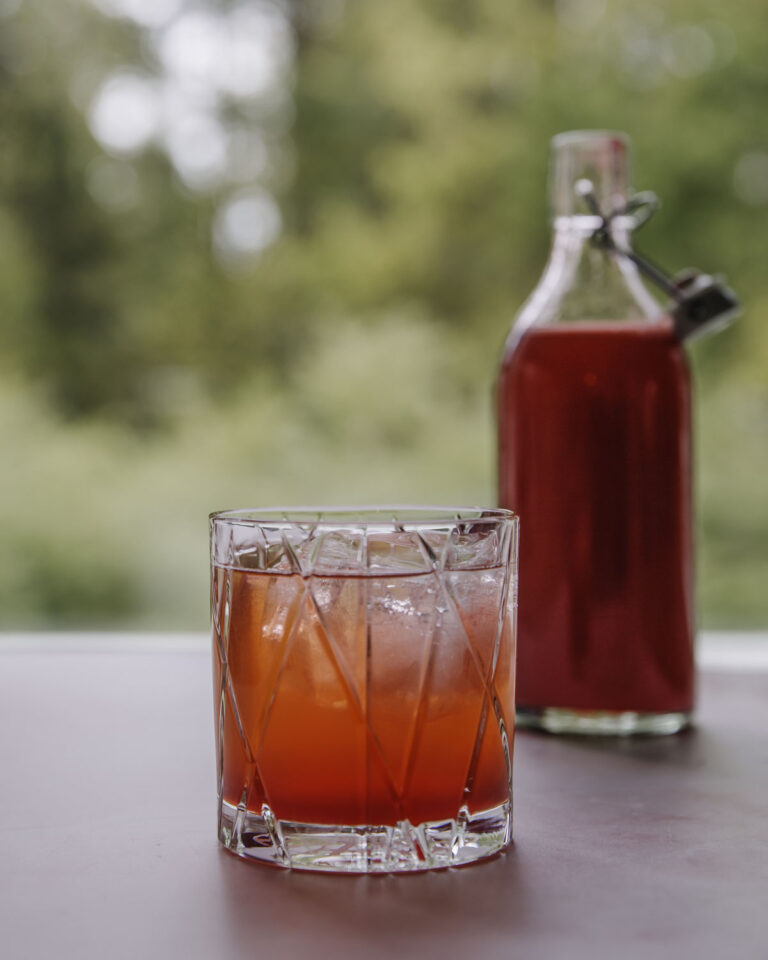 Puolukkamehu valmistuu helposti ilman mehumaijaa. Kuvassa mehua on lasissa, taustalla on mehupullo.