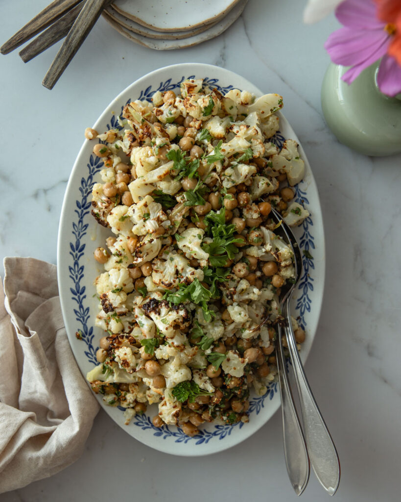 Paahdettu kukkakaali-kikhernesalaatti on soikealla tarjoiluilautasella.