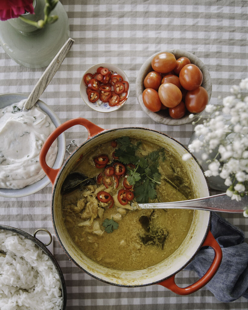 Kanarengang on maailman paras kanapata. Kuvassa pata on ruudullisella pöytäliinalla. Kuvassa on myös korienteridippi, riisikulho, tomaatteja ja chilirenkaita. 