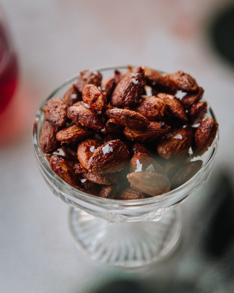 Parhaat mausteiset pähkinät  - kokeile helppoja reseptejä.

Kuvassa on harissamanteleita. Paahdetut mantelit ovat jalallisessa lasikulhossa. Kulhon ympärys on epätarkka.