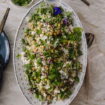 Jennifer Aniston -salaatti on ruokaisa, nopea ja helppo salaatti. Salaatti on soikealla valkoisella lautasella, jossa on pieniä sinisiä kuvioita reunoilla. Salaatin päällä on sinisiä ja valkoisia syötäviä kukkia. Vasemmassa reunassa ja ylhäällä näkyy lautasia sekä pieni yrttejä sisältävä kulho.