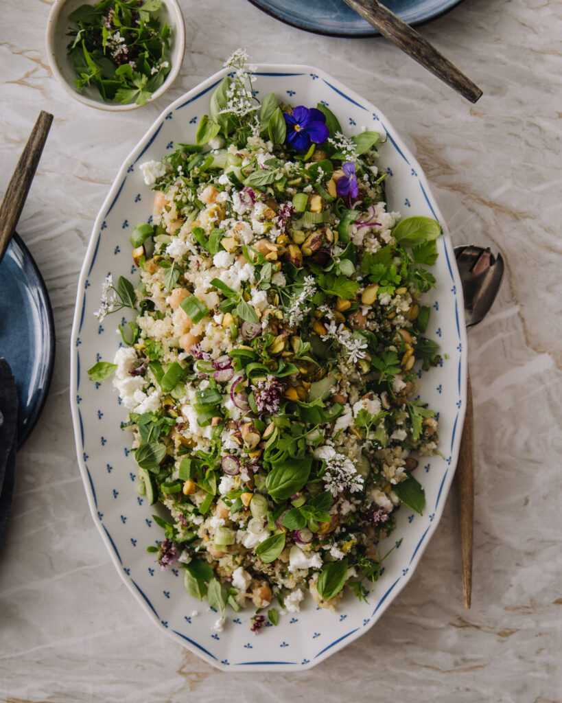 Jennifer Aniston -salaatti on ruokaisa, nopea ja helppo salaatti. Salaatti on soikealla valkoisella lautasella, jossa on pieniä sinisiä kuvioita reunoilla. Salaatin päällä on sinisiä ja valkoisia syötäviä kukkia. Vasemmassa reunassa ja ylhäällä näkyy lautasia sekä pieni yrttejä sisältävä kulho.