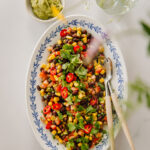 Papusalsa on helppo tehdä. Kuvassa salsa on soikealla tarjoilulautasella. Lautasella on myös ottimet. Oikeassa reunassa ja ylhäällä on epätarkkana kasveja. Klo 11 kohdalla on pienessä kipossa avokadotahnaa. Kuva on otettu ylhäältäpäin.