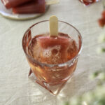 Glögimehujää on helppo herkku ja siitä tulee myös ihana drinkki. Kuvassa mehujää on lasissa. Päälle on kaadettu kuohuviiniä. Kuva ylälaidassa on mehujäitä lautasella.