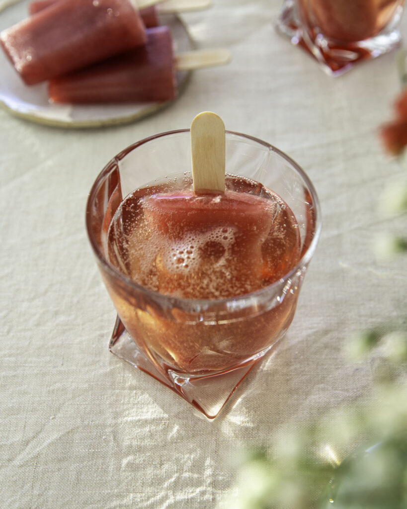 Glögimehujää on helppo herkku ja siitä tulee myös ihana drinkki. Kuvassa mehujää on lasissa. Päälle on kaadettu kuohuviiniä. Kuva ylälaidassa on mehujäitä lautasella.