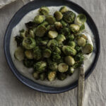 Paahdetut ruusukaalit & fetavaahtoa on helppo ja herkullinen pikkuruoka tai lisäke. Kuvassa fetavaahto on sinisellä lautasella. Ruusukaalit ovat kekona vaahdon päällä. Klo viiden kohdalla on lusikka.