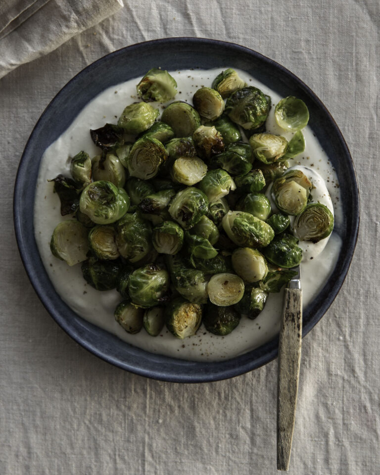 Paahdetut ruusukaalit & fetavaahtoa on helppo ja herkullinen pikkuruoka tai lisäke. Kuvassa fetavaahto on sinisellä lautasella. Ruusukaalit ovat kekona vaahdon päällä. Klo viiden kohdalla on lusikka.