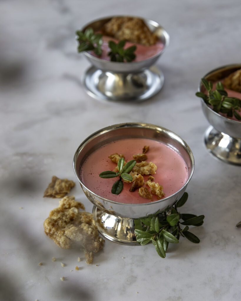 Puolukkaposset on helppo jälkiruoka. Kuvassa posset on metallisissa jälkiruokakulhoissa. Possetin päällä on rapeita kaurakeksejä sekä koristeena puolukanoksa.