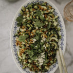 Rapea riisisalaatti on maukas ja ruokaisa salaatti, johon riisi paahdetaan rapeaksi uunissa. Kuvassa salaatti on soikealla vadilla. Salaatin päällä on pähkinärouhetta sekä yrttejä.