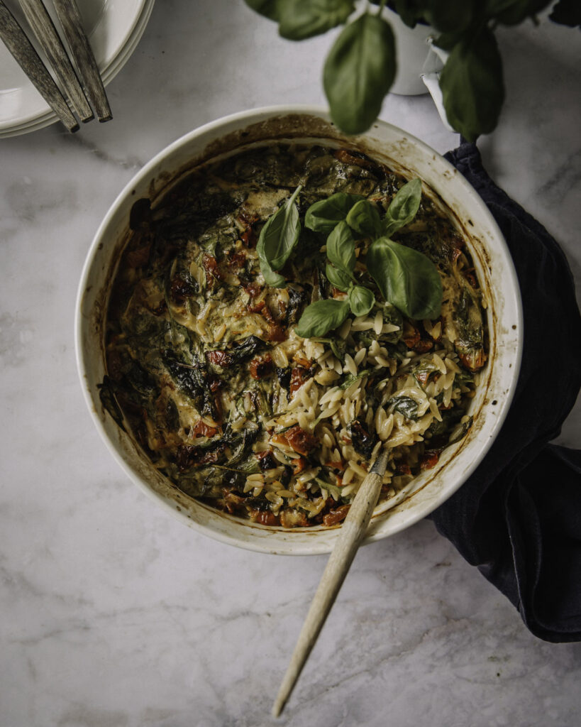 Marry me -pasta on helppo yhden astian versio suositusta arkiruoasta. Kuvassa ruoka on valkoisessa pyöreässä uunivuoassa. Ruoan päällä on basilikanlehtiä. Basilikaa on myös kuva yläreunassa, samoin kuin lautaset ja haarukat.