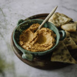 Muhammara on itämainen paprikatahna. Kuvassa oranssinvärinen tahna on vihreässä kulhossa. Vieressä on ohutta leipää.