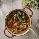 Kurpitsacurry on helppo ja maukas pataruoka. Kuvassa curry on punaisessa padassa. Ruoan päällä on korianteria. Kuva on otettu ylhäältäpäin.