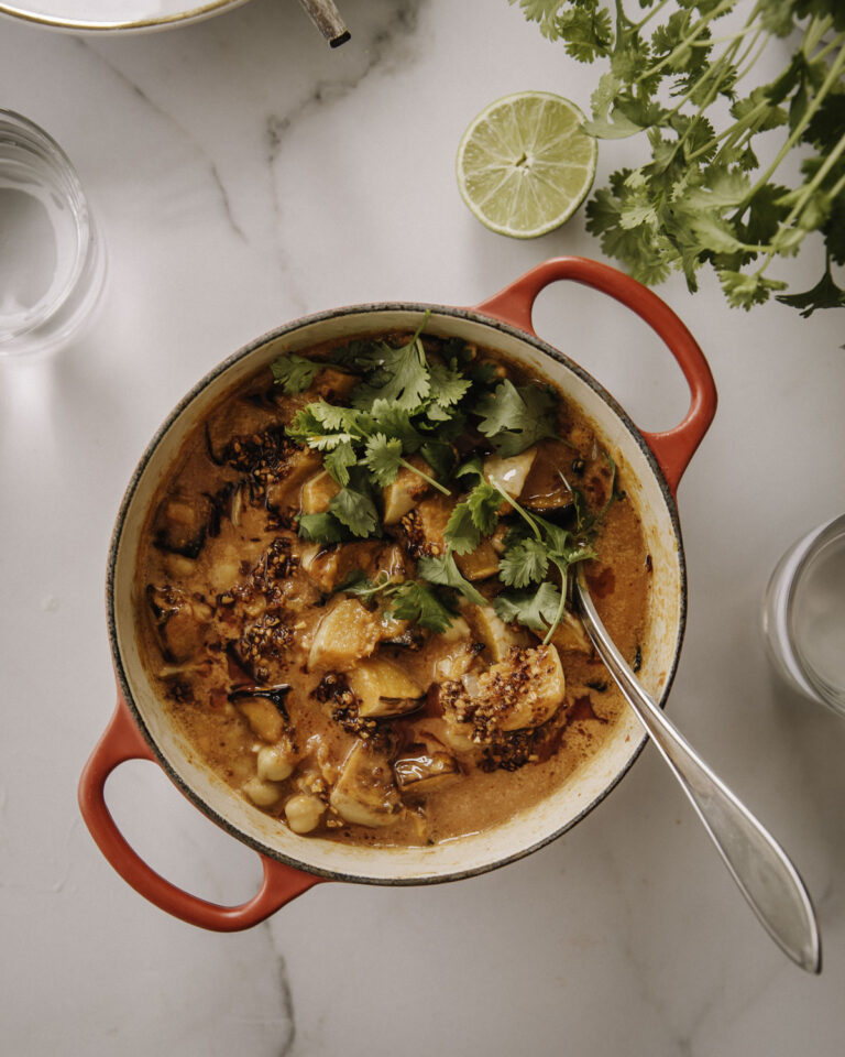 Kurpitsacurry on helppo ja maukas pataruoka. Kuvassa curry on punaisessa padassa. Ruoan päällä on korianteria. Kuva on otettu ylhäältäpäin.