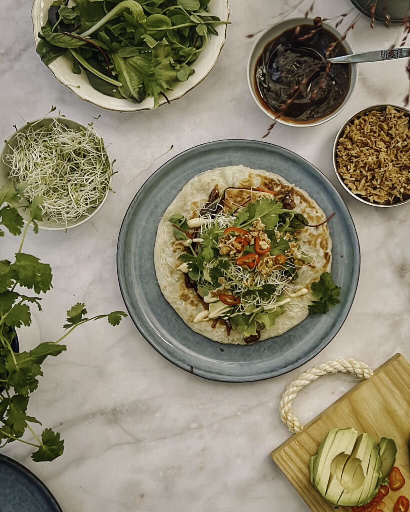 Shanghai-tacot yhdistää aasialaiset maut tacojen helppouteen. Keskellä on sinertävällä lautasella partha-letun päälle koottu Shanghai-taco ja ympärillä on kipoissa tacon aineksia. Kuva on otettu ylhäältäpäin.